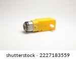 Small photo of A DC motor with its power socket equipped with a yellow gearbox side view on a white background. DIY materials for the electronics hobbyist.