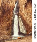 Small photo of The stream of a powerful waterfall flows down between the rocks into a mountain river. Fullscreen photo. The nature of the Caucasus
