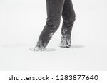 Man slowly and hard walking in deep, white, fresh snow. Snowstorm in winter day. Side view.