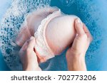 Housewife's hands washing light pink women's bra in the blue basin. Dry cleaning concept. Clothes care. Chores of maid. Regular washing. 
