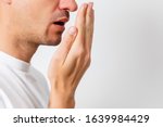 Bad breath. Halitosis concept. Young man checking his breath with his hand.