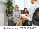 Small photo of Female psychologist counseling parent. Serious single mom and sad unhappy child sitting on sofa and discussing social behaviour, ADHD disorder diagnosis, apathy or adolescent depression with therapist
