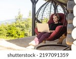 Woman working on computer outdoor with mountain view.