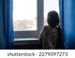 Kid's Depression. Unhappy Little Girl Sitting Feeling Lonely Near Window Hugging Herself At Home. Copy Space.
