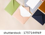 Close-up colorful mail envelopes on beige background flat lay with copy space, top view. Mailing concept isometric. White paper blank mockup for letters, greeting card, postcard, invitation