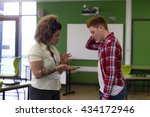 Small photo of Teenage student being told off by his teacher at school.