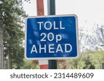 Small photo of Rectangle blue toll 20p ahead sign with trees in background, concept illustration.