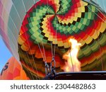 The inside of a brightly coloured hot air balloon as fire is used to prepare it for take off. Taken in Aswan, Egypt.