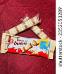 Small photo of Kinder bueno chocolate candy bar on maroon background. Kinder bueno by Italian confectionery manufacturer ferrero