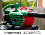 Small photo of Gas powered leaf blower and empty gas canister sit atop of a trash can after a proposed ban on gas powered blowers