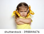 Angry little girl with yellow bows and yellow T-shirt over white background, sign and gesture concept