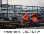 Male and Female Railway engineers with orange safety jackets check the railway