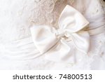 A close up of a wedding dress with a large silk bow