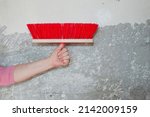 Small photo of painting and priming wall paint. hand hold fetlock on gray grunge cement wall background. brush for repair and construction. building concept. work tool and equipment. repairman working with broom.