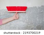 Small photo of hand hold fetlock on gray grunge cement wall background. brush for repair and construction. building concept. work tool and equipment. repairman working with broom. painting and priming wall paint.
