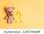 Children's toy with a Childhood Cancer Awareness Yellow Ribbon on yellow background. Childhood Cancer Day February, 15.