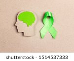 World mental health day concept. Green awareness ribbon and brain symbol on a brown background.