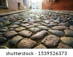 Old town in Europe at sunset with retro vintage cobble stone. cobble paving Stone background for walking. Cobblestone street in sunlight with a wall made from granite blocks