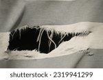 Small photo of hanging teared rag spread isolated on black background , can use like a background or any texture. hole in the tissue. Unbleached beige fabric with torn stitch, hole and loose threads
