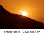 silhouette of alone man standing on horizon line, top of mountain and looking at sunset cloudy sky. back, rear view. Young male standing on high rock at sunrise and enjoying view of evening nature