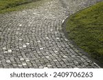 Cobblestone path s-curve. Cobbled stone path in summer park. stoned path in the meadow. green grass around. 