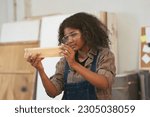 Small photo of Female carpenter working in wood workshop. Female joiner wearing safety uniform and working in furniture workshop