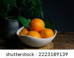 Small photo of Dogo story Japan Citrus fruit with green leaves on the white wood. Home gardening. Mandarine oranges. Tangerine oranges. Orange color.