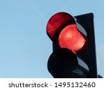 Red signal on traffic light in focus and blue sky in the background.