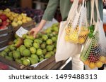 Woman chooses fruits and vegetables at farmers market. Zero waste, plastic free concept. Sustainable lifestyle. Reusable cotton and mesh eco bags for shopping