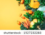 Autumn vegetables on trendy yellow background. Top view. Vegan and vegetarian diet, harvest concept. Ingredients for cooking - pumpkin, tomatoes, cucumber, pepper, kale, broccoli, celery.