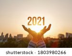 Hands show New Year 2021 against the background of the sun.