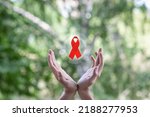 Hands support the symbol of the fight against HIV AIDS and cancer.