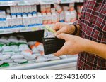 Money And Supermarket. Man counts his money 'Argentine Pesos' In The Supermarket. shelves background.
