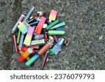 Small photo of A collection of discarded electronic cigarette vapes have been collected and placed together over a worn concrete floor