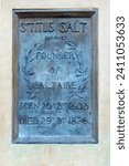 Small photo of Saltaire, UK 01 10 2024 : Plaque below the sculpture of Titus Salt who created a mill village outside Bradford to improve the lives of his workers in victorian times. Now a unesco world heritage site