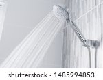 Fresh shower behind wet glass window with water drops splashing. Water running from shower head and faucet in modern bathroom.