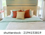 Small photo of Beautiful modern bedroom furnished in complimentary pastel shades of red and green pillow.