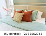 Small photo of Beautiful modern bedroom furnished in complimentary pastel shades of red and green pillow.