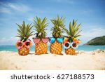 Family of funny attractive pineapples in stylish sunglasses on the sand against turquoise sea. Tropical summer vacation concept. Happy sunny day on the beach of tropical island. Family holiday