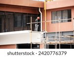 Small photo of facade installation, men at work, workers install, on a high-rise building. Installation in an office on a construction site. curtain wall systems are new, panel, frame, multilayer, construction.