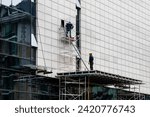 Small photo of facade installation, men at work, workers install, on a high-rise building. Installation in an office on a construction site. curtain wall systems are new, panel, frame, multilayer, construction.