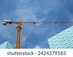 Small photo of part of a house under construction and a crane. tower crane, mobile crane lifting and crane element boom - construction site concept, practical use of lifting equipment for suburban construction.
