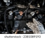 Small photo of row of ignition coils for a four-cylinder engine where the ignition coil socket for cylinder number four is being removed using the right hand. Jogja, 28 October 2023