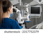 Small photo of Female dentist using dental microscope treating patient teeth dental clinic office. undergoing treatment by experienced dentist using microscope
