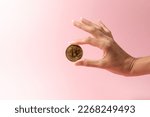 cryptocurrency, finance and business concept - close up of female hand holding golden bitcoin over pink background