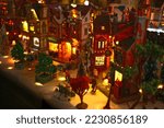 Christmas village street scene with large illuminated houses, antique shop, led lights, miniature figurines and snow-covered trees