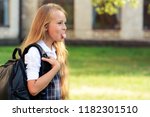 Small photo of girl schoolgirl with a backpack near school shows tongue crooked funny and preposterous girl near school cheerful naughty