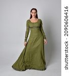 Small photo of Full length portrait of red head girl wearing green Celtic medieval gown. Standing pose with elegant pose. isolated on studio background