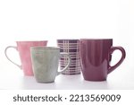 Small photo of Four cups for herbal tea in a palette, gray, lilac, purple, pink, diversity and friendship, limbo ethereal white background, on white surface