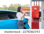 Woman standing holding a cup of coffee while waiting to charge an electric car at a city public charger station